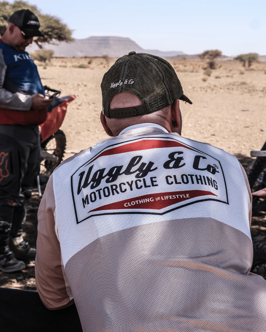 MX rider resting in a long-sleeve motocross jersey with 'Uggly & Co Motorcycle Clothing' logo