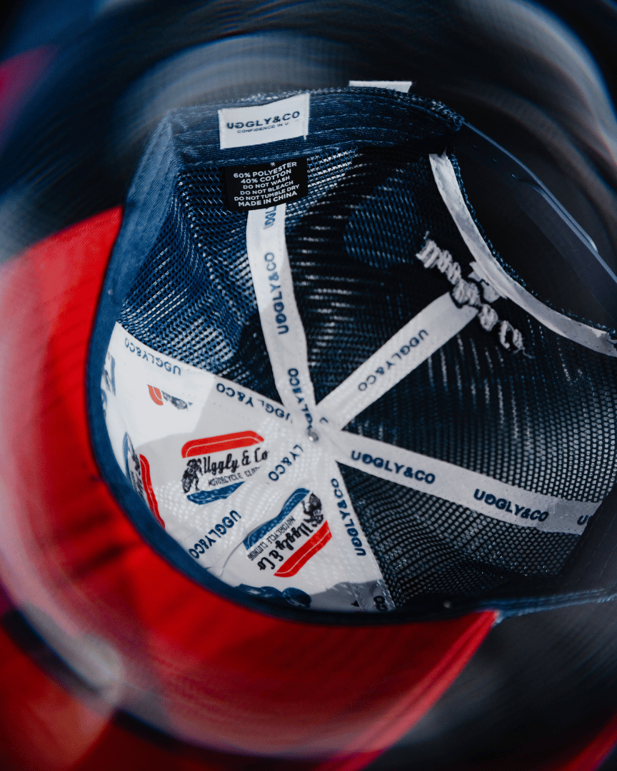 A close up of the inside of a red, white and blue flat-track cap with Uggly&Co branding on the seams