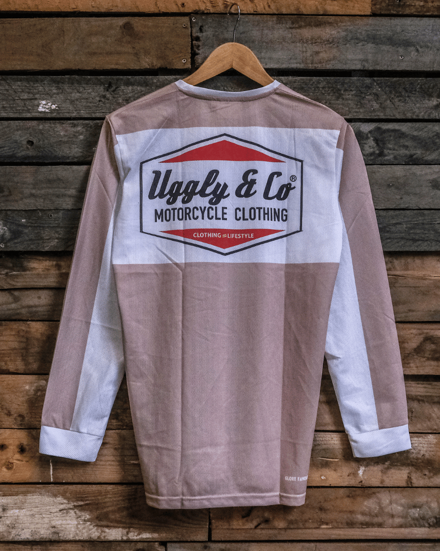 Long-sleeve motocross jersey with 'Uggly & Co Motorcycle Clothing' logo on a wooden background