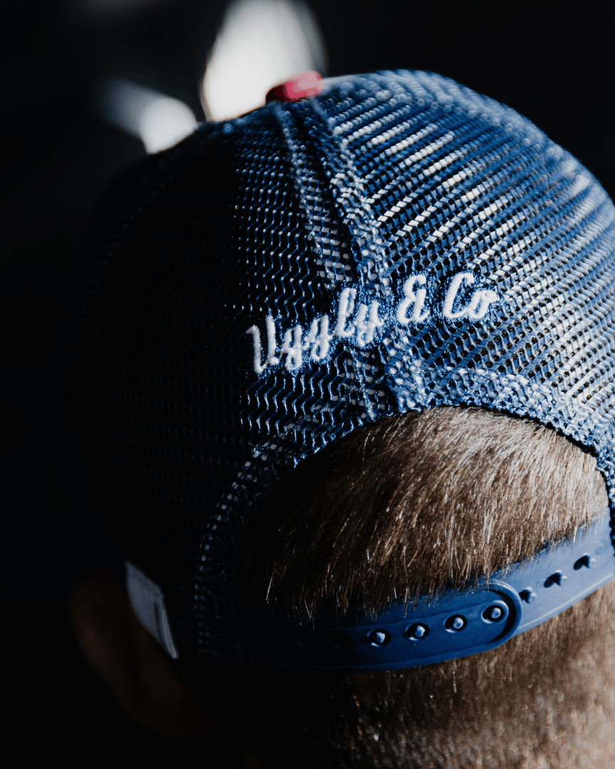 Rear view of a model wearing a red, white and blue flat-track cap with a frayed Uggly&Co badge featuring a motorcycle racing theme