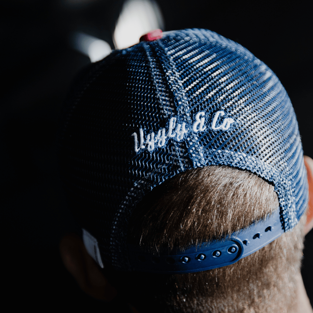 Rear view of a model wearing a red, white and blue flat-track cap with a frayed Uggly&Co badge featuring a motorcycle racing theme
