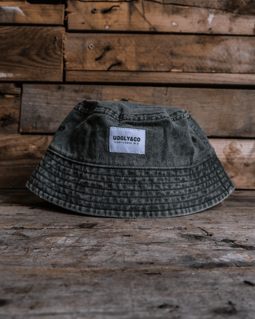 Vintage green bucket hat with an Uggly&Co label on a wooden surface