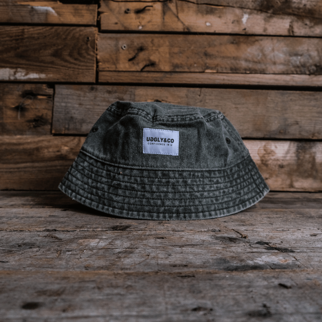 Vintage green bucket hat with an Uggly&Co label on a wooden surface