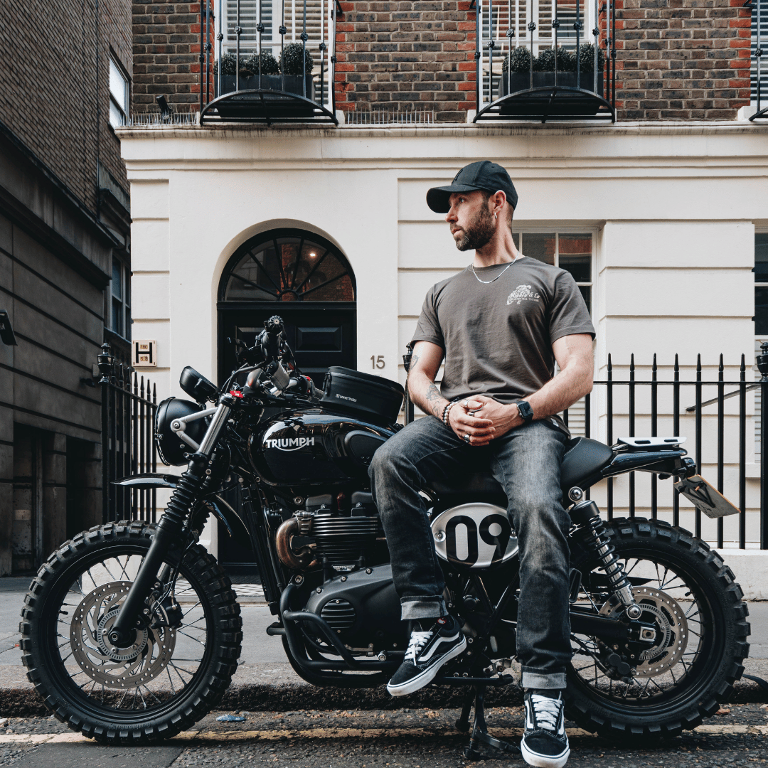 Man sitting on a Triumph motorcycle in an urban setting