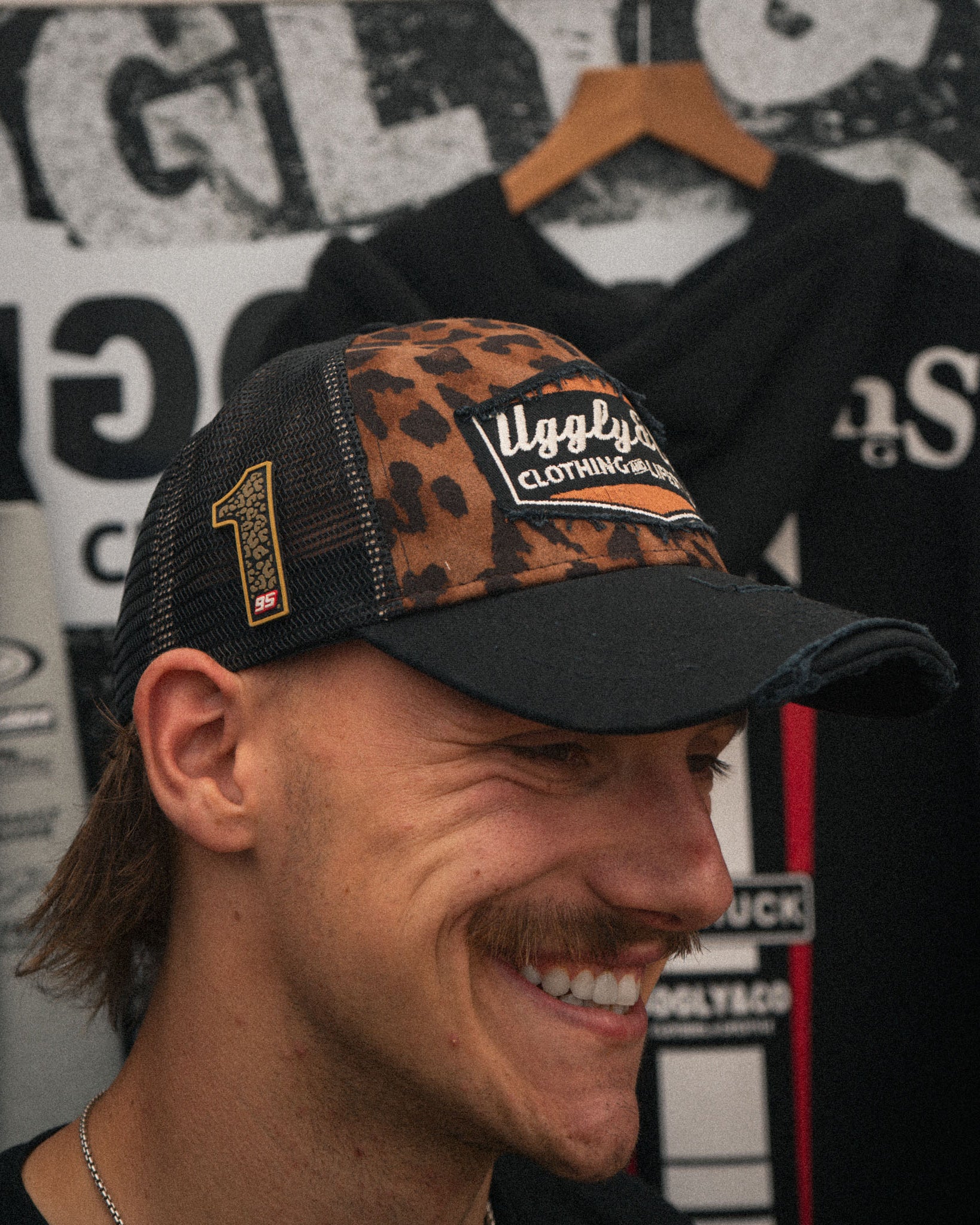Oscar Lawrence in the race paddock wearing the Leopard Print Diamond Trucker Hat