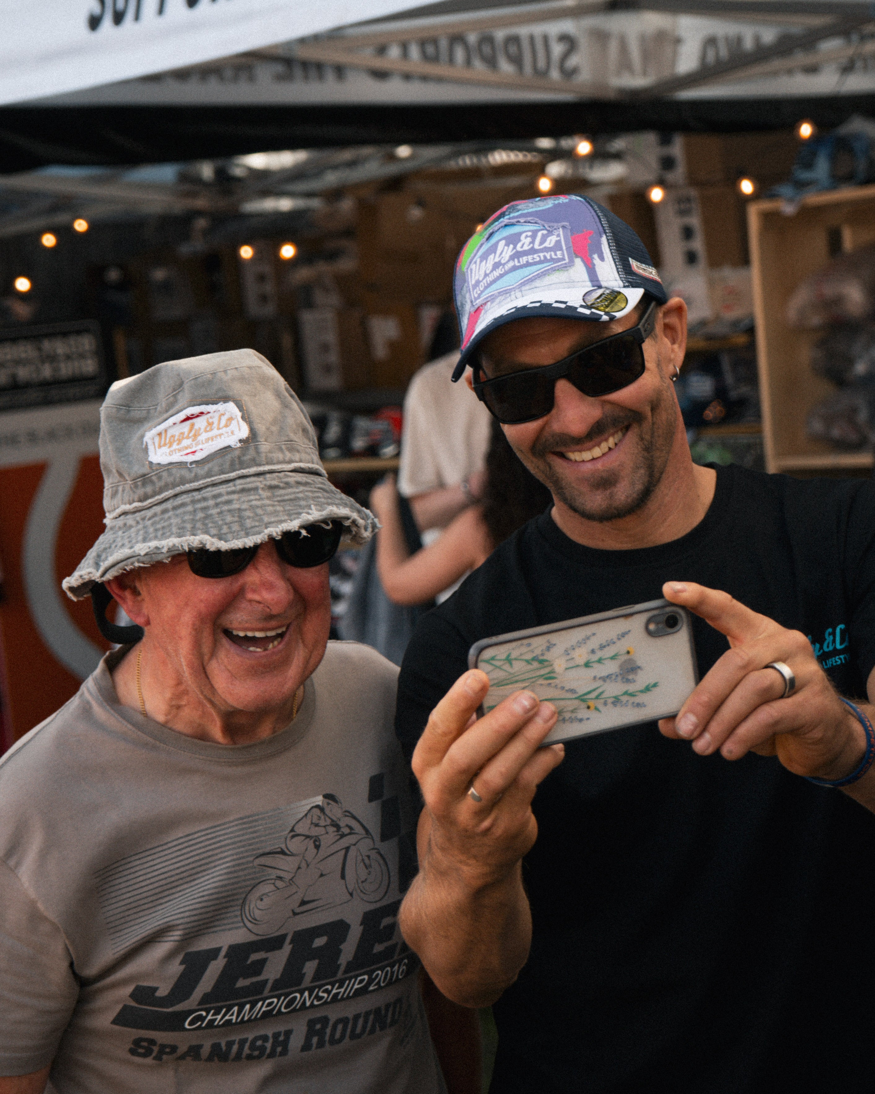 Josh Brookes taking a photo his signature uggly and co baseball cap with a fan in his acid wash bucket hat