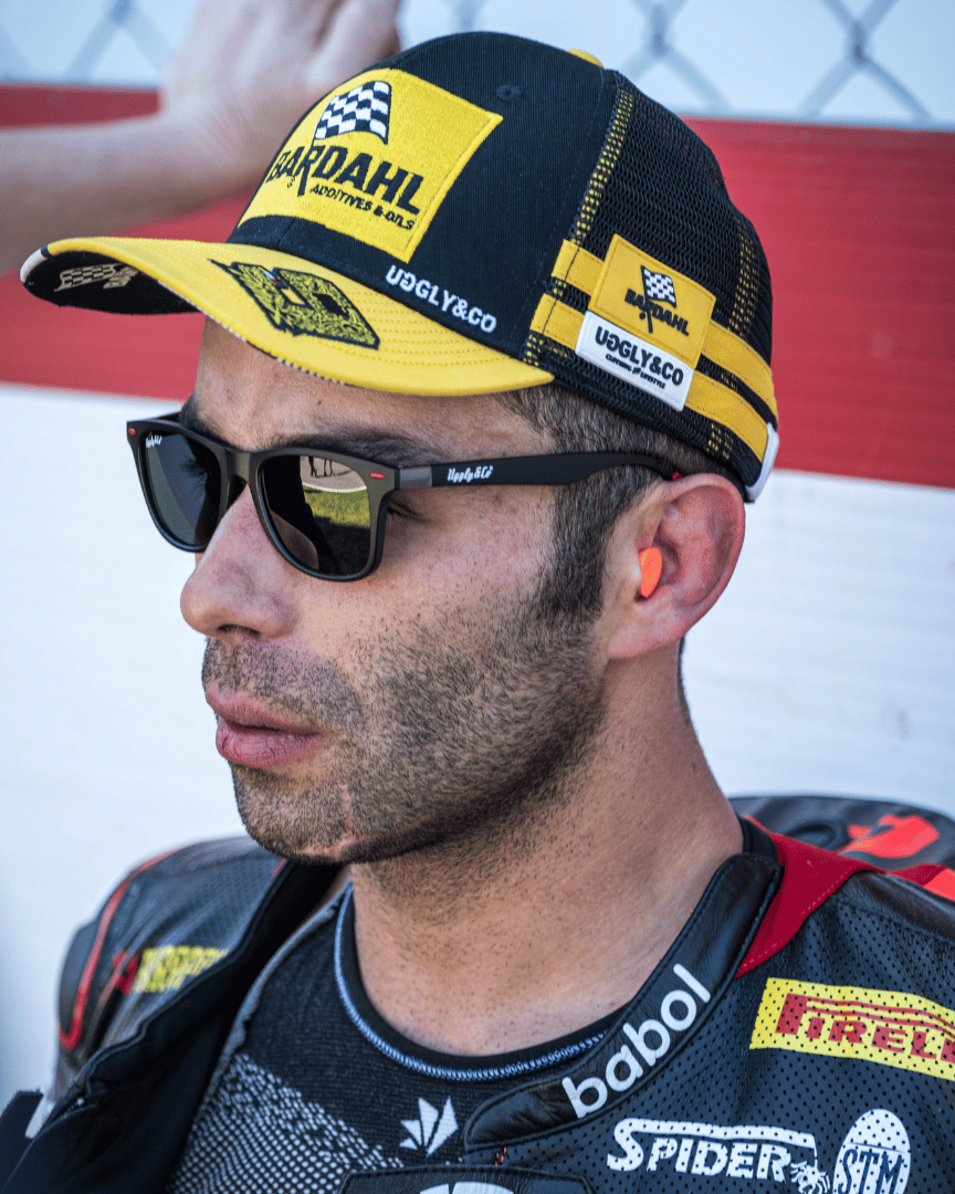 Side view of Danilo Pertrucci wearing a yellow and black Uggly&Co Bardahl Danilo Pertrucci #9 merchandise trucker hat