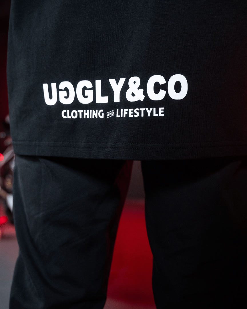Close up of the Uggly&Co logos on the bottom of the back of a Carl Cox motorsport and Team Classic Suzuki black and red t-shirt