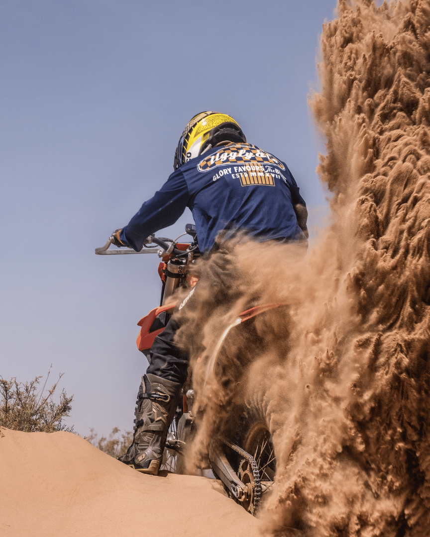 Wheel spinning a motocross bike in the desert in a blue Uggly&Co MX shirt