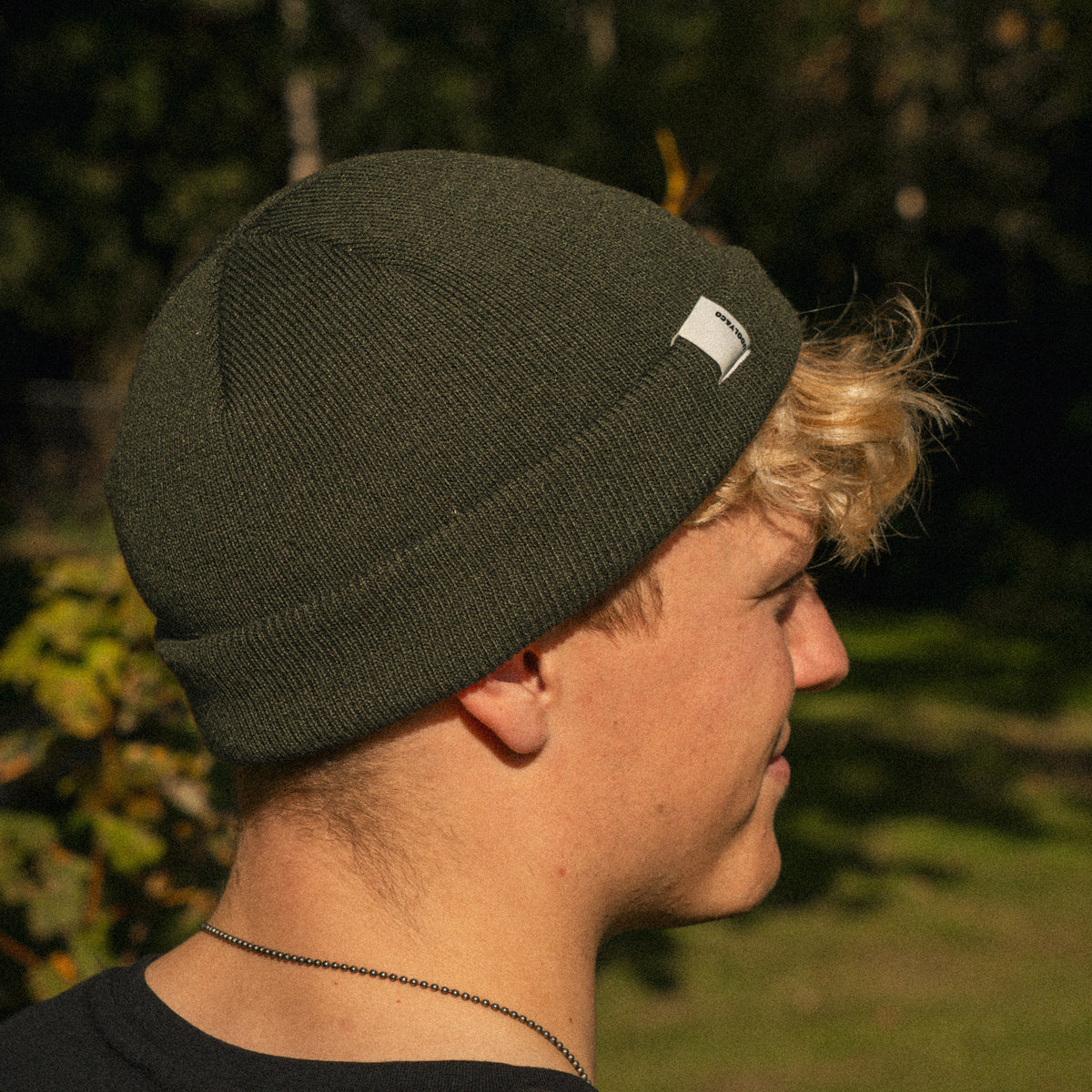 Close-up of the logo detail on the Olive Fisherman Beanie worn by Rhys Irwin
