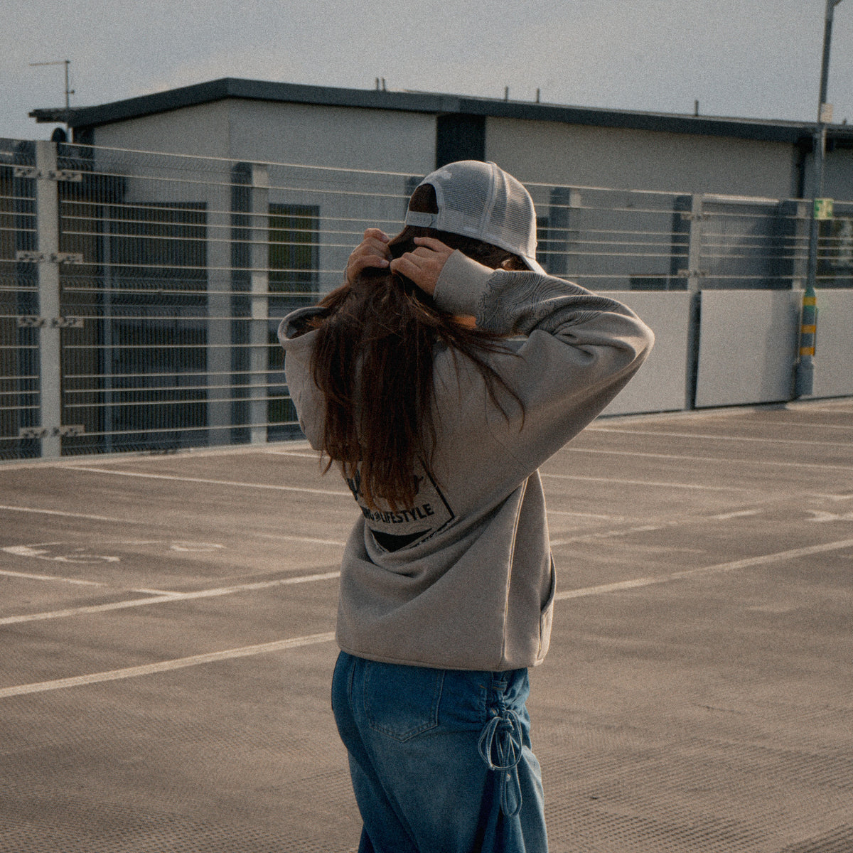 Side profile of a female model wearing the Silver & Grey Diamond Trucker Hat