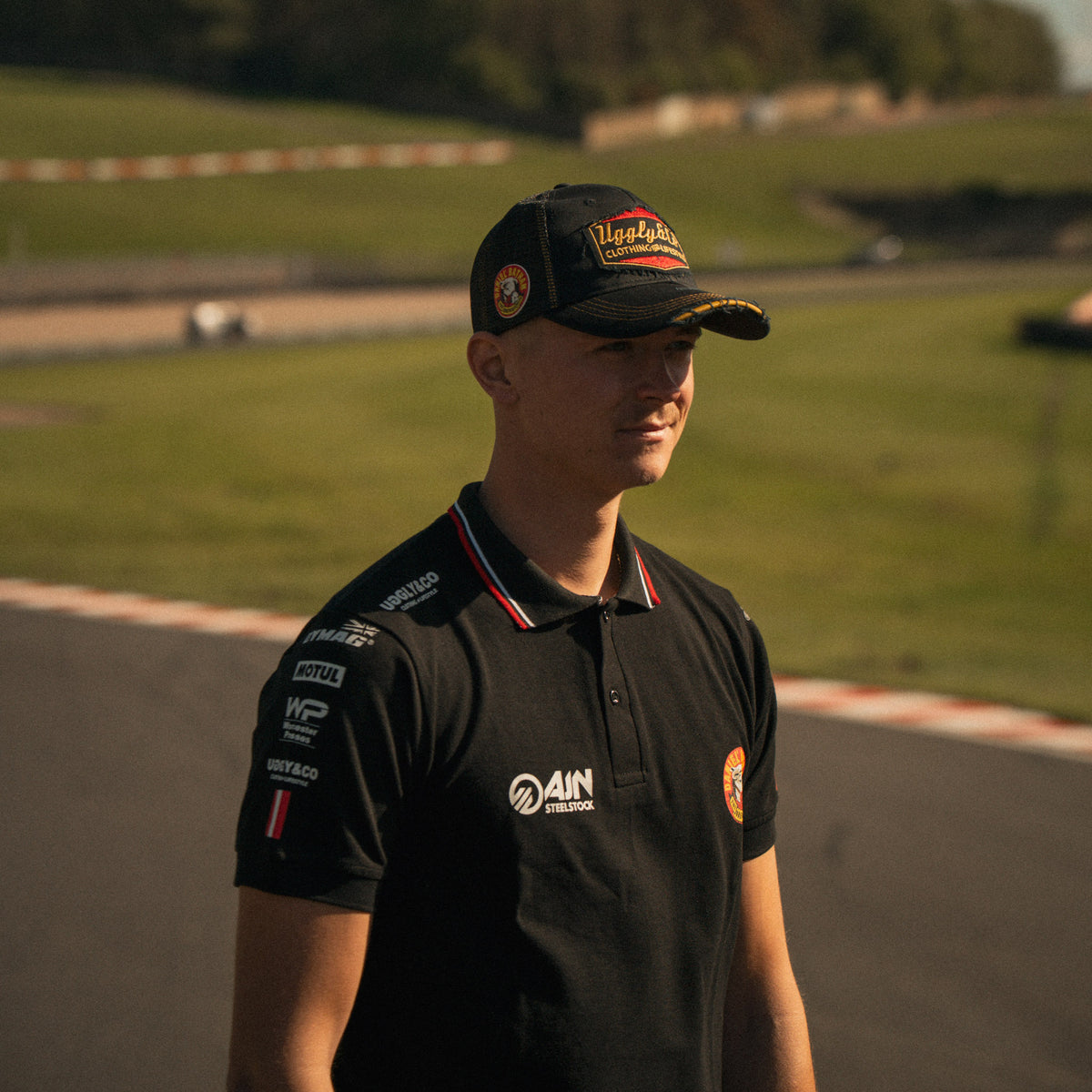Side view of Storm Stacey wearing the Bathams Racing x AJN Steelstock Road Racing Polo