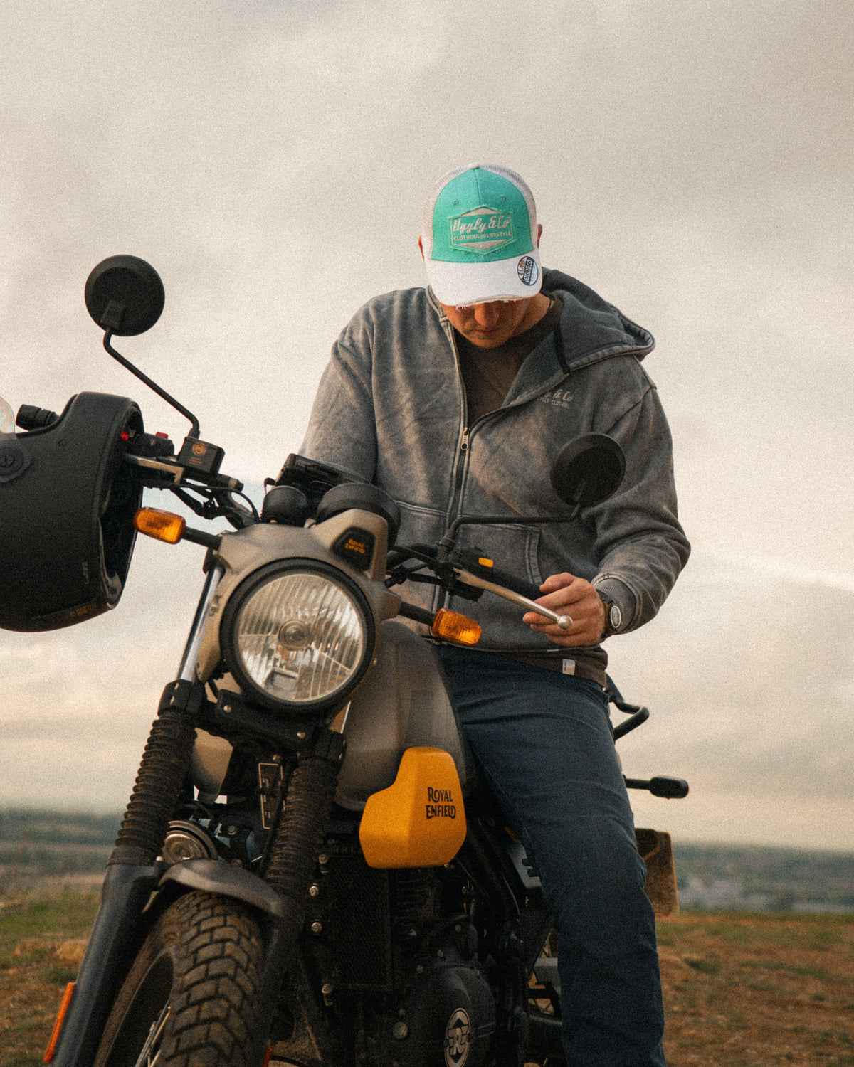 Rider wearing the Uggly&Co Turquoise & White Diamond Trucker Hat, sitting on a Royal Enfield Scram 411