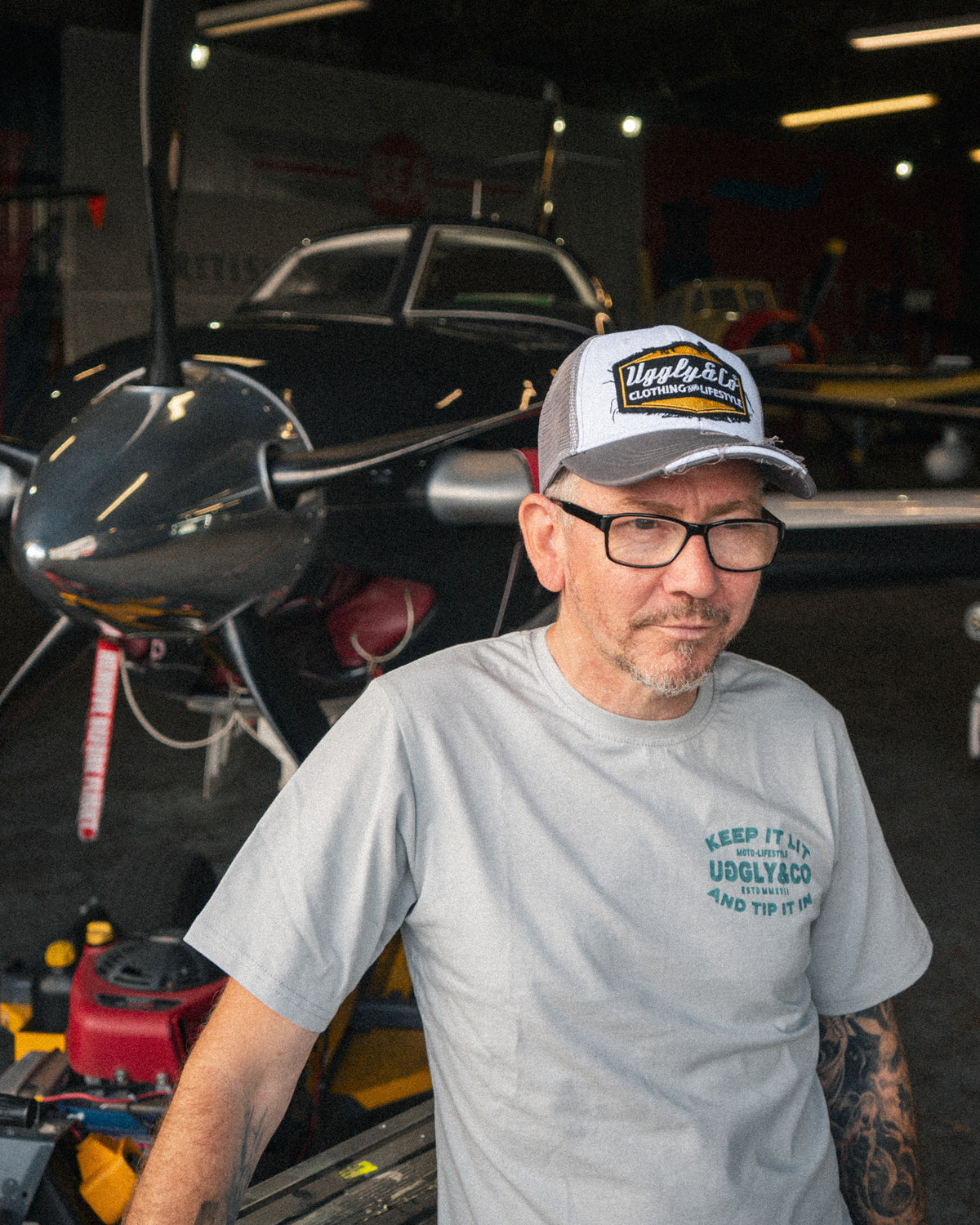 Uggly & Co Diamond Trucker Cap worn by a man wrapping a van in a large aircraft hangar.