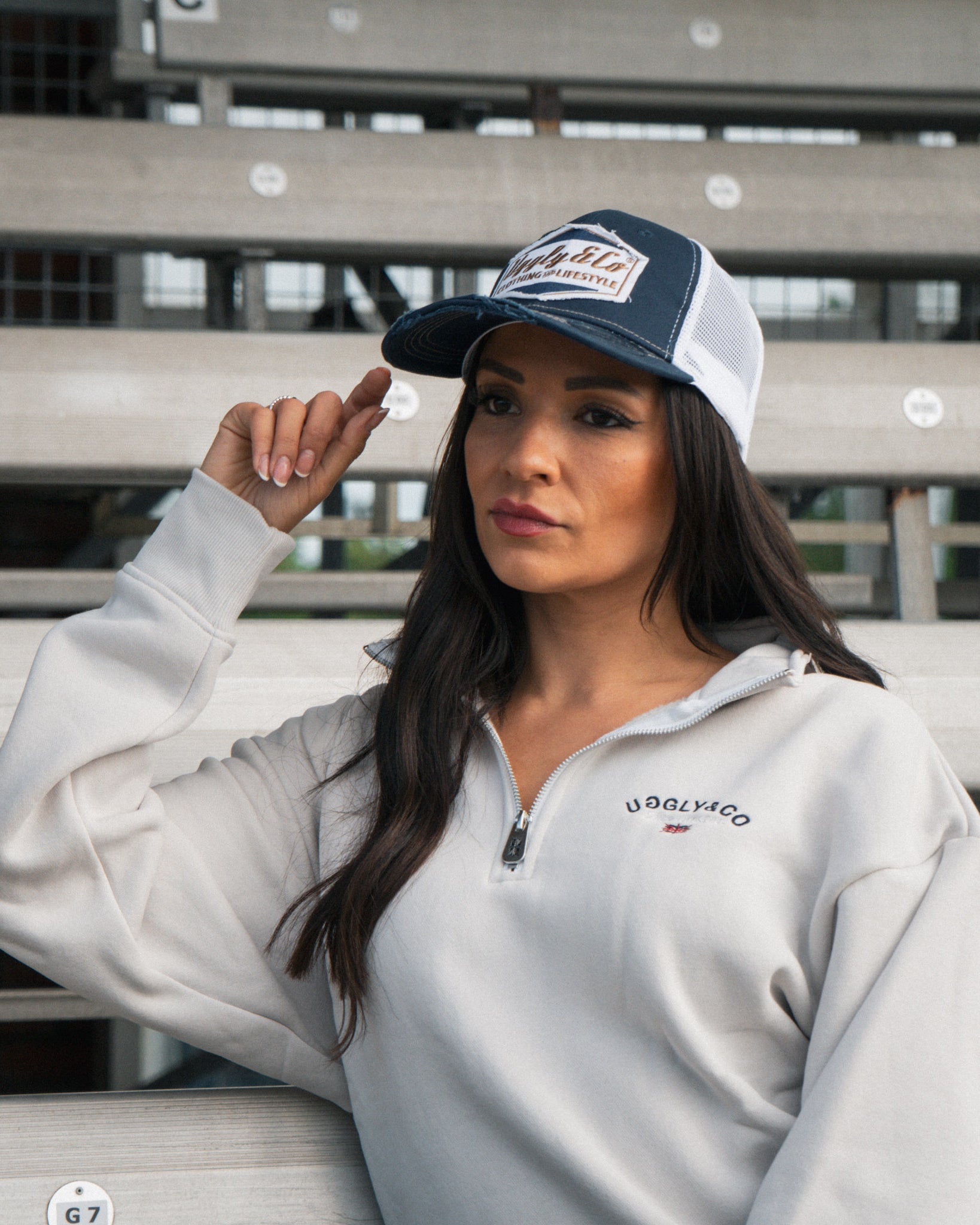 Female model wearing the Uggly&Co Night Blue and Gold Diamond Cap in the grandstand at a race event