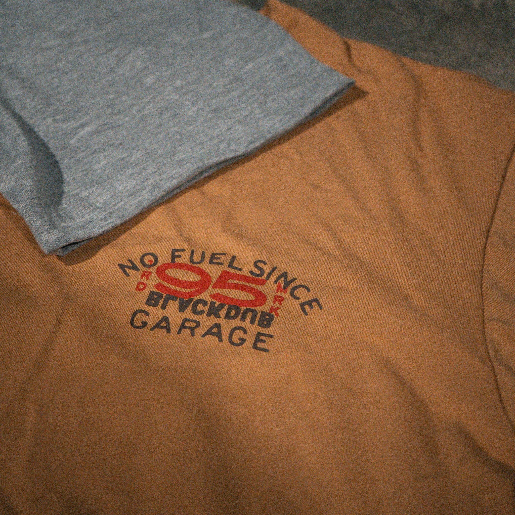 Brown and grey Uggly & Co No Fuel-frSince ’95 T-shirts shown together from the front.