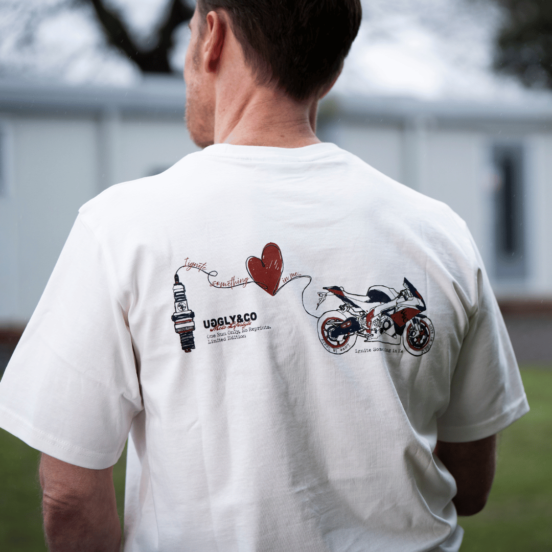 Rear view of a model wearing a limited edition Valentine’s white t-shirt with spark plug heart graphic, and Uggly&Co logo with a blurred background
