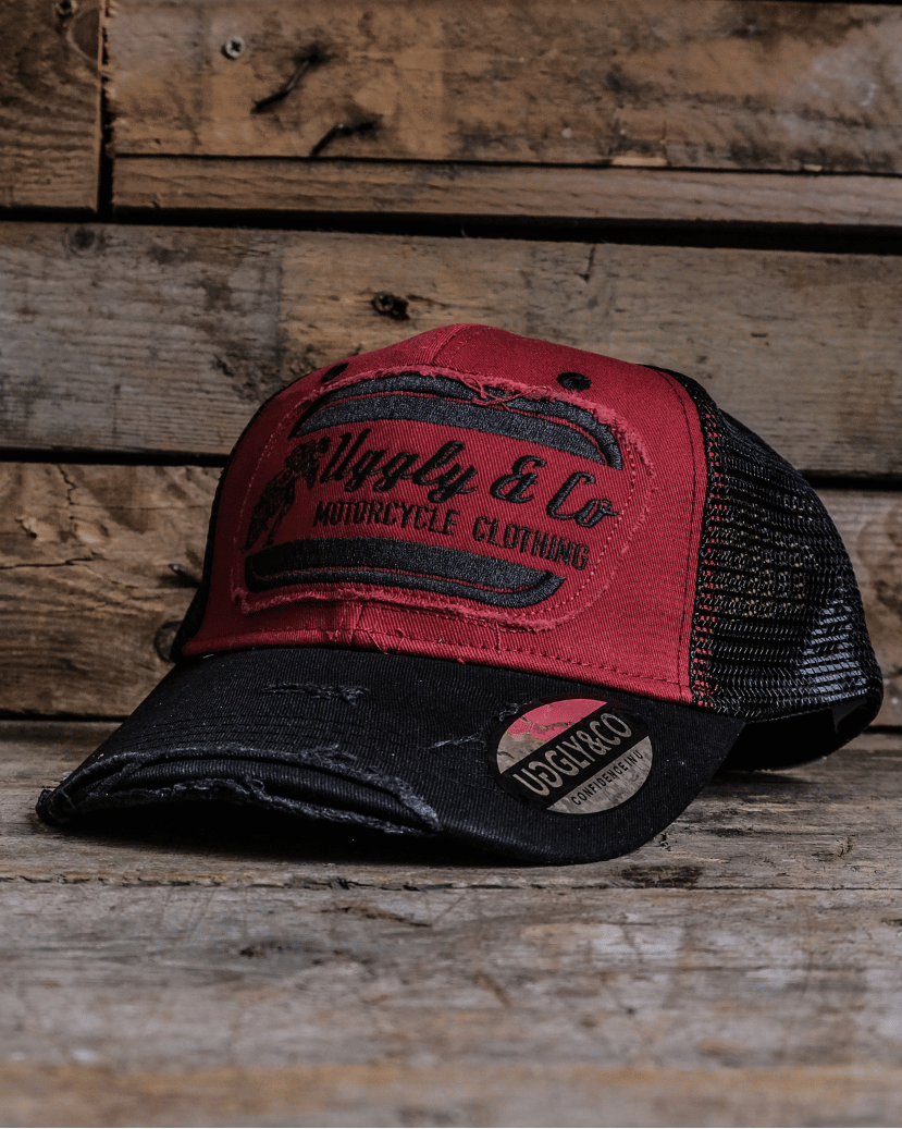 Red and black trucker hat with branding on a wooden surface