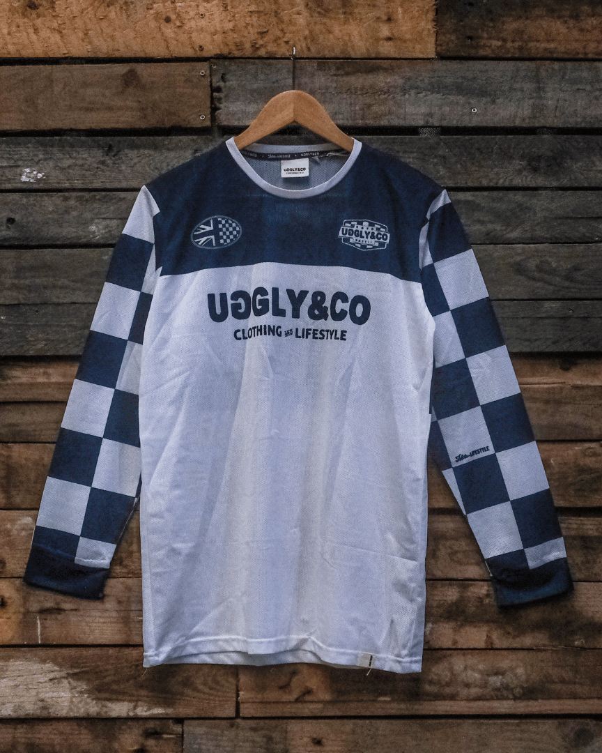 Checkered long-sleeve MX shirt with 'Uggly & Co' branding on a wooden background facing forwards