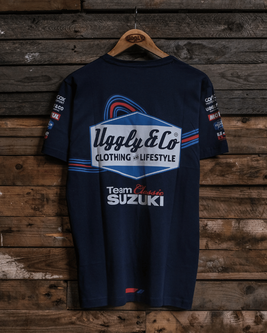 Rear view of a navy Team Classic Suzuki blue t-shirt with Uggly&Co branding on a wooden background