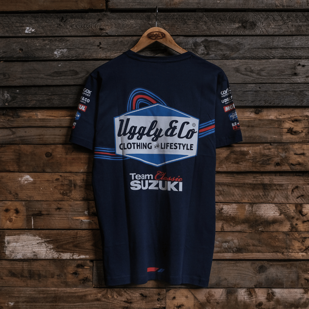 Rear view of a navy Team Classic Suzuki blue t-shirt with Uggly&Co branding on a wooden background