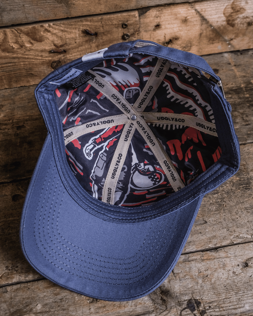 Inside view of a royal blue Uggly&Co vintage cap with a white and red design inside, displayed on a wooden surface.