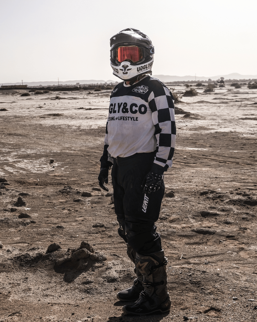 Motocross rider in full gear in the desert wearing a chequered Uggly&Co MX shirt
