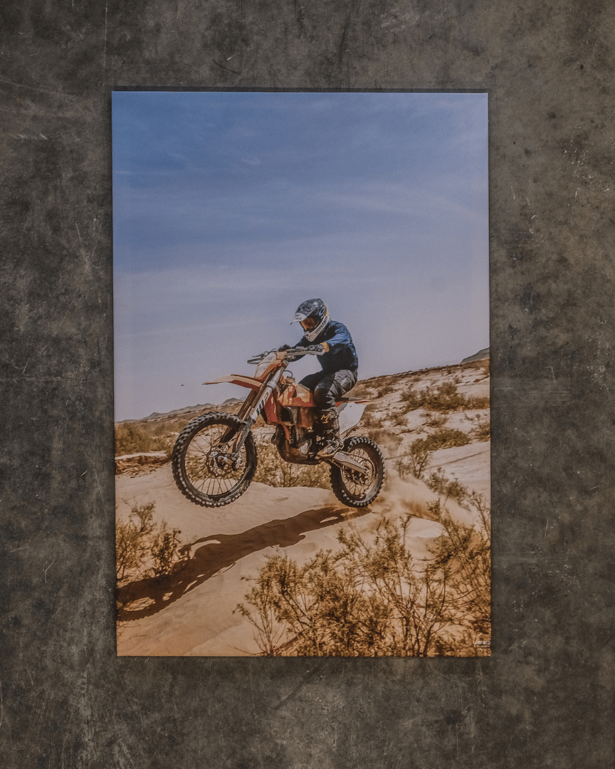 A canvas print featuring a motocross rider jumping a bike in the air with a desert background.