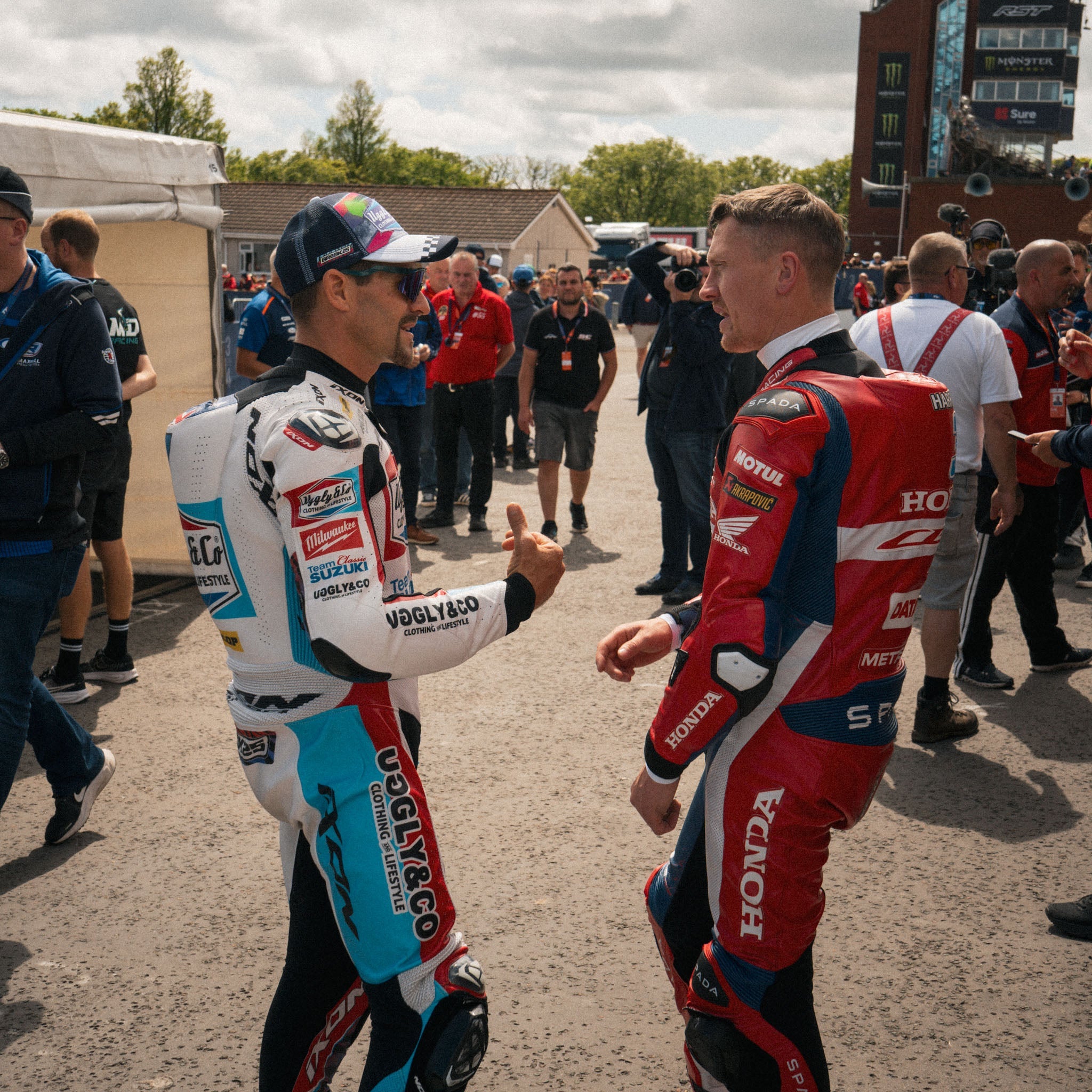 dean Harrison and josh brookes talkling in busy paddock at race event