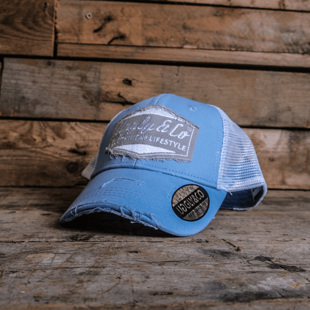 Blue trucker hat with a white mesh back and visible branding on a wooden surface.
