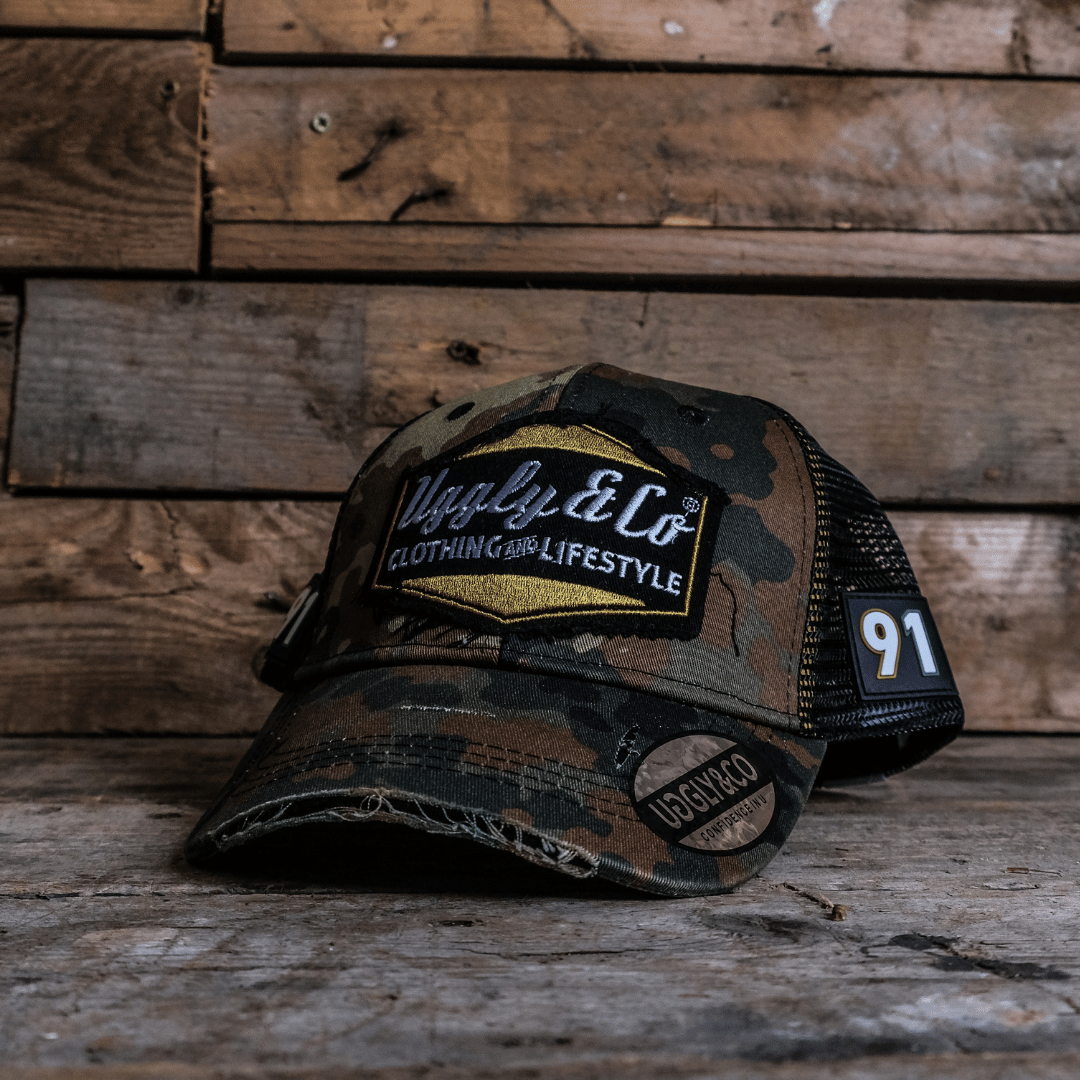 Camouflage trucker hat front view with Uggly&Co logo on a wooden background