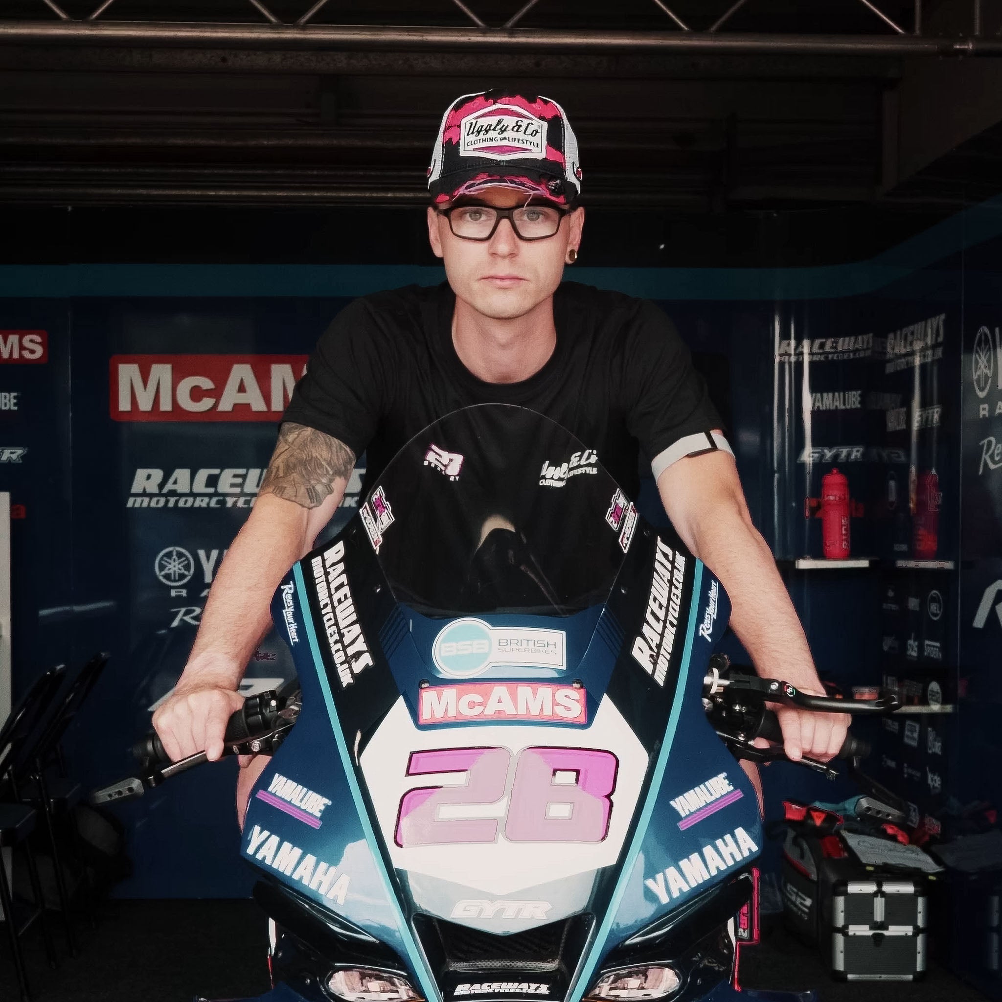 Bradley Ray seen wearing a pink black and white trucker hat whilst sat on his mcams bike