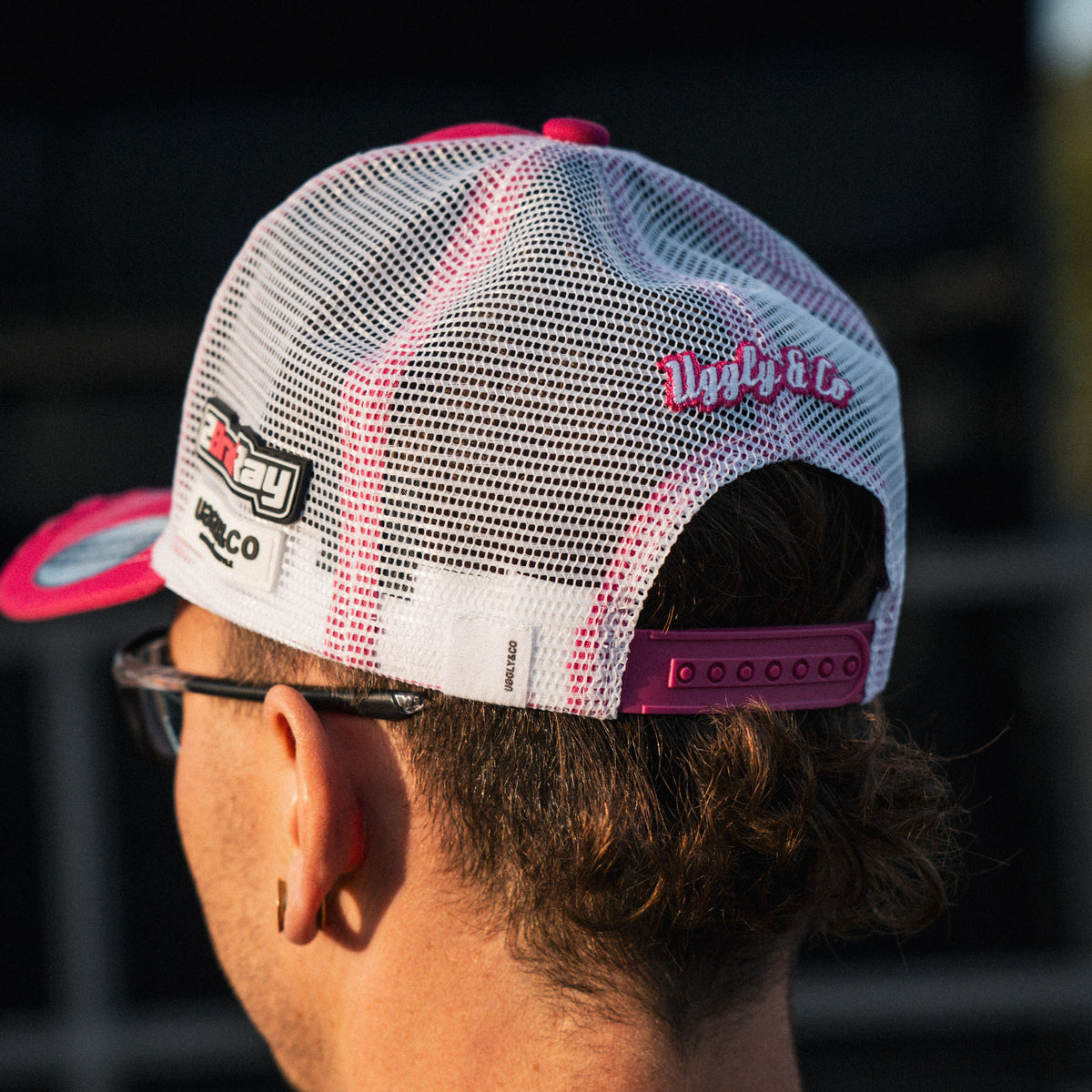 photo showing the mesh and closing of pink and white trucker hat worn by Bradley Ray