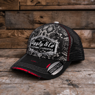 A black and white trucker hat with a distressed pattern on the front panel and brim, featuring a white 'Uggly & Co' logo patch. The back mesh is black with thin red stitching accents, and the hat is photographed on a rustic wooden plank surface.