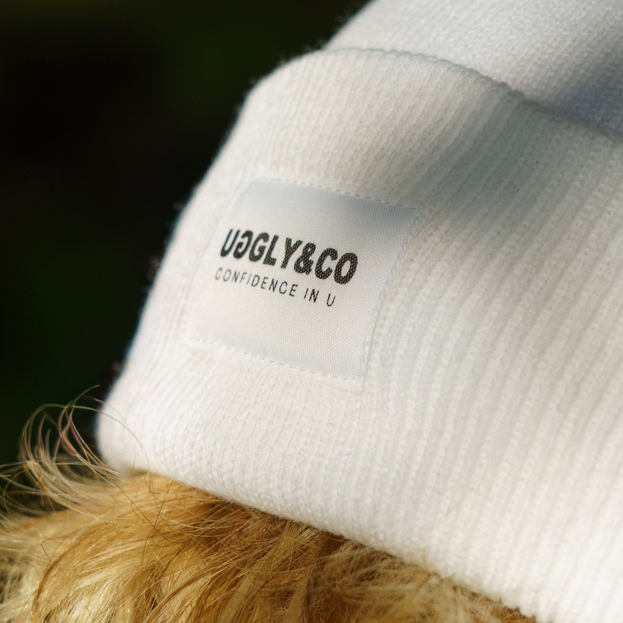 close up shot showing the logo on a white uggly and co beanie