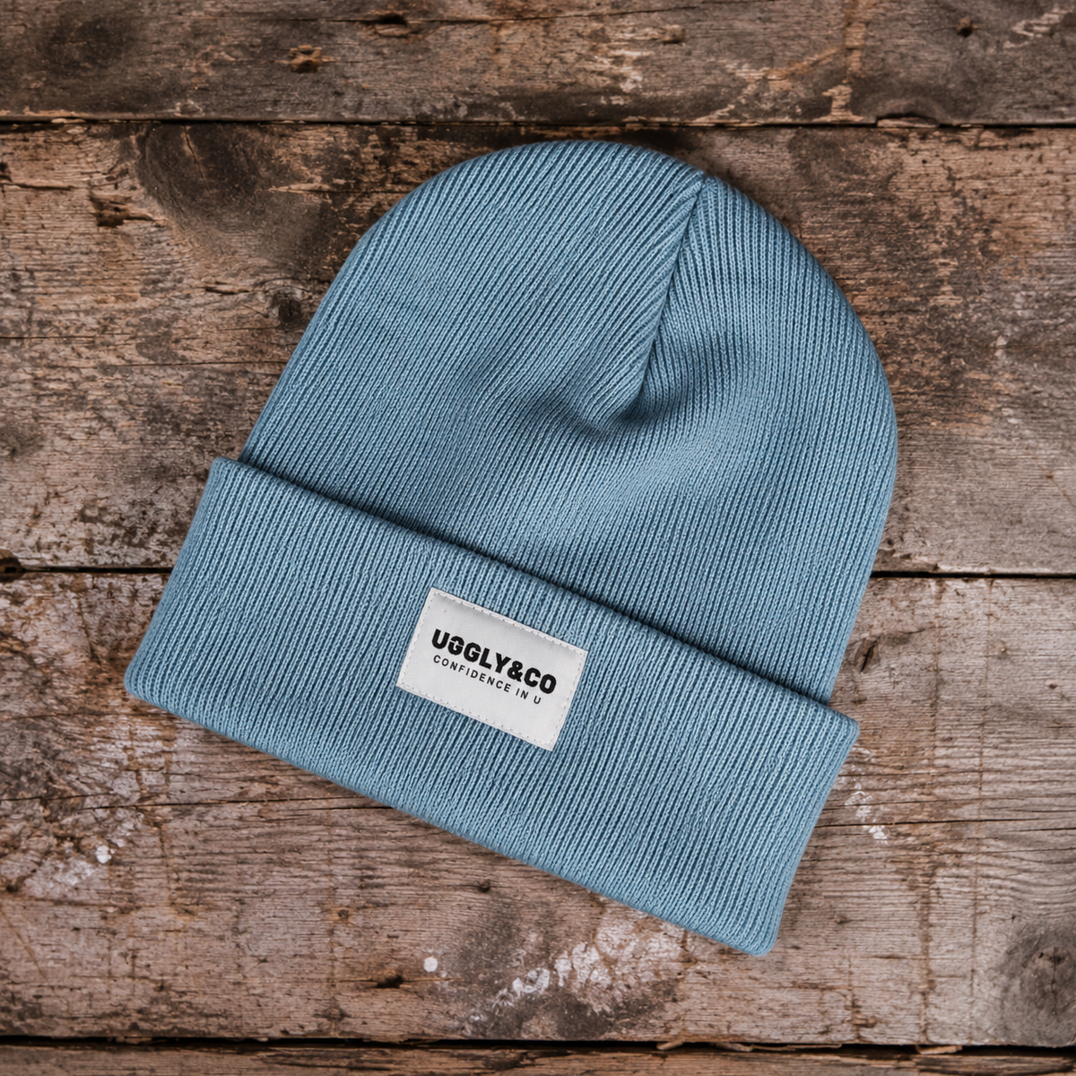 dusty blue knit beanie shown on wood background. Product photo showing the texture of the wool beanie
