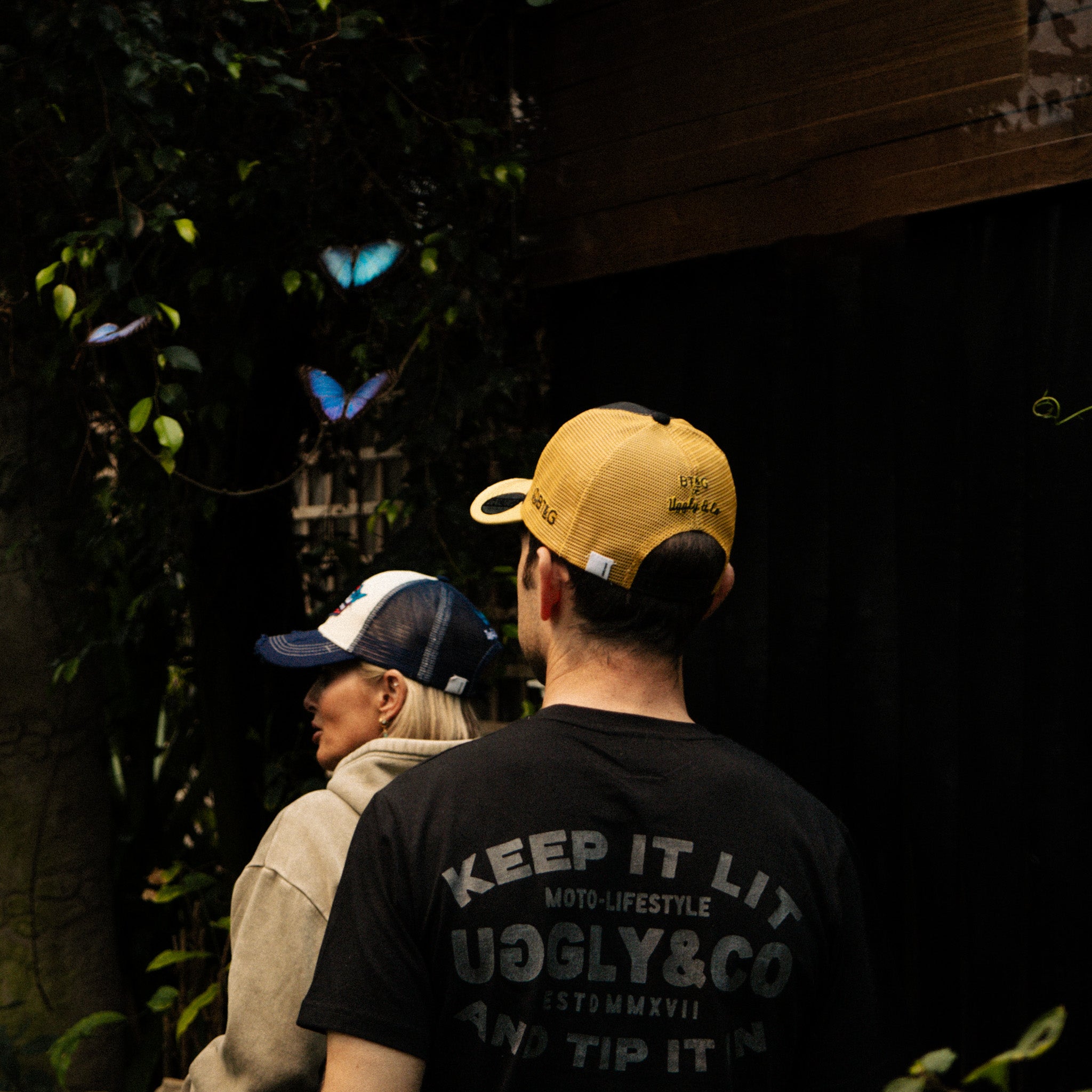 Sylvain Guintoli and wife in the butchers tap trucker hat stood in forest with butterflies