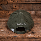 product photo showing the back logo on green baseball cap on a wood background
