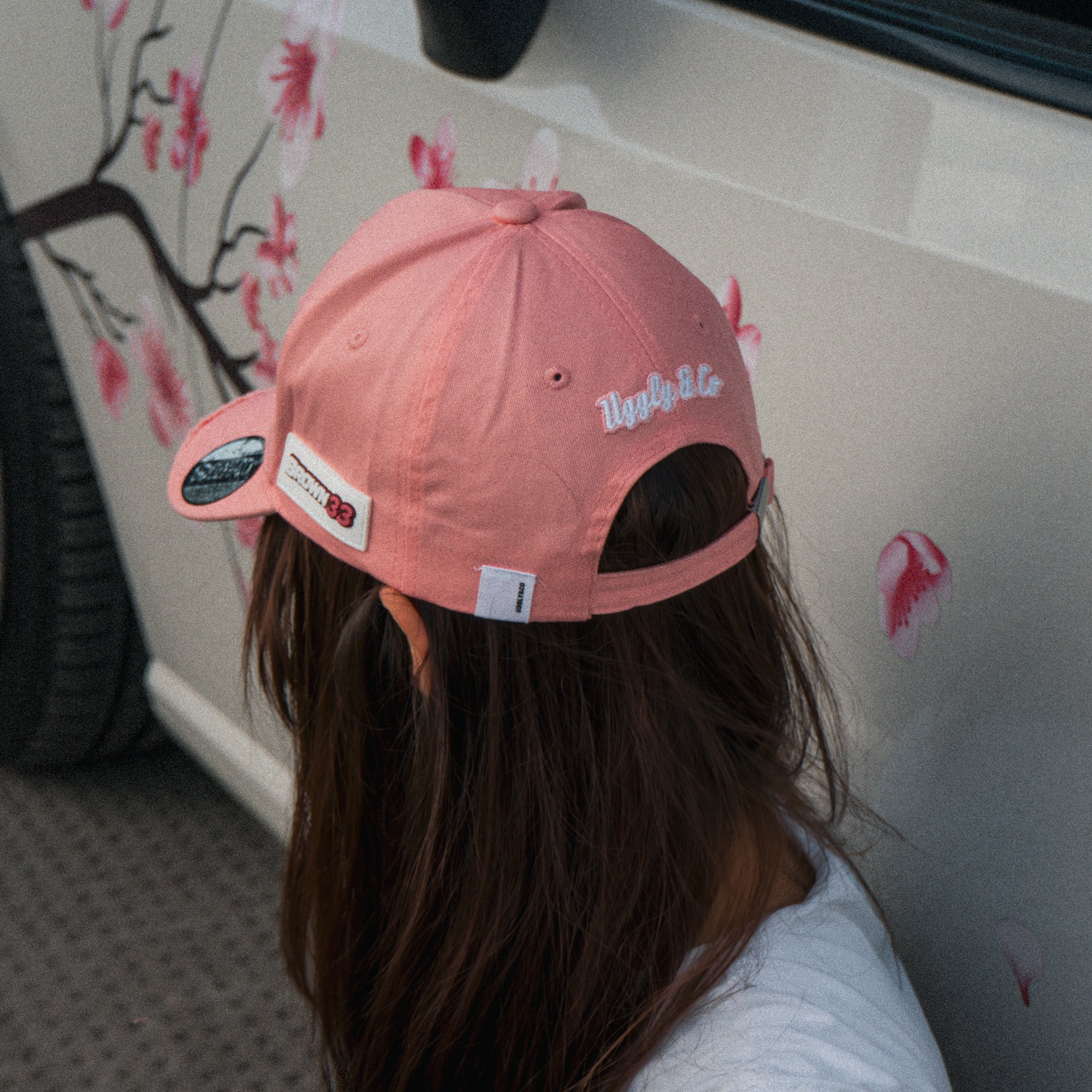 Women’s lifestyle photo featuring the Washed Pink Vintage Cap in front of a modified car