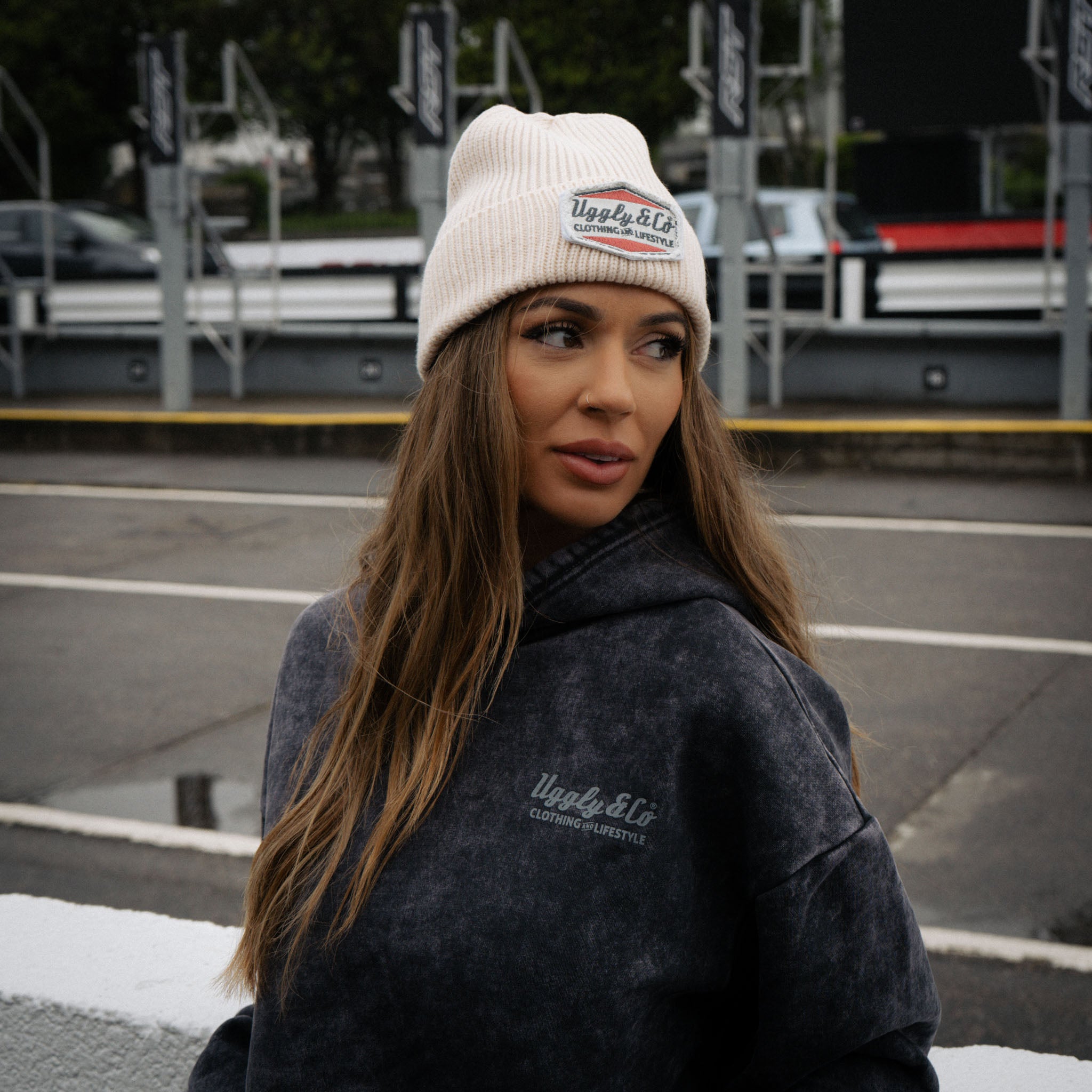 Close lifestyle shot of a girl wearing the beige Diamond beanie in pit lane