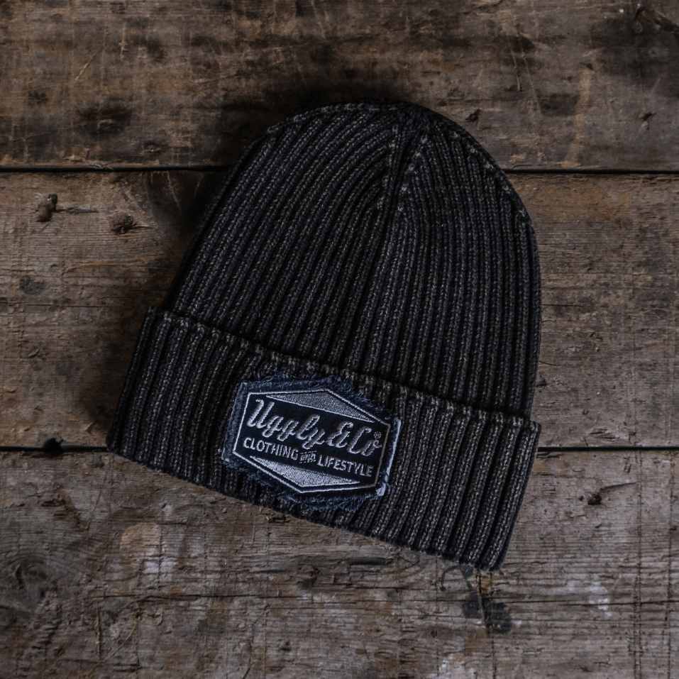 Black beanie with a brand patch on a wooden surface