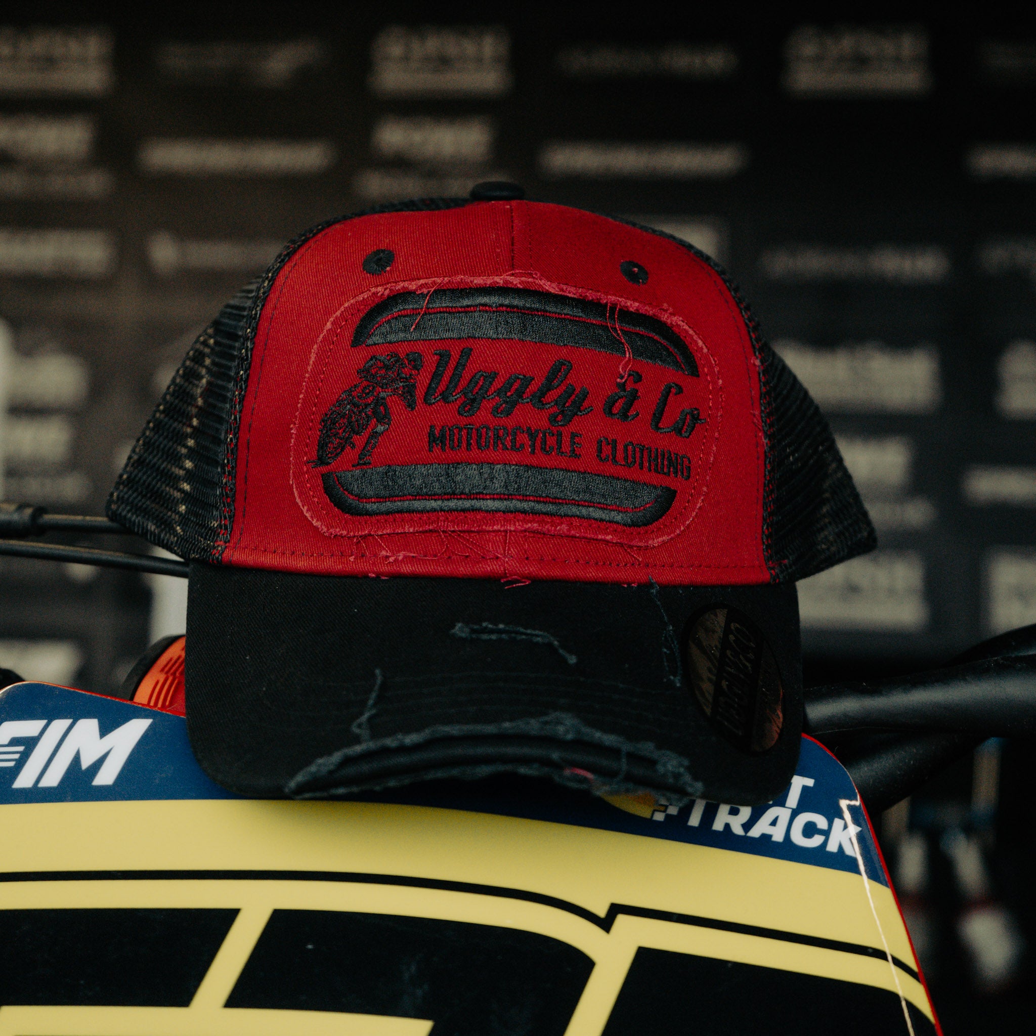 Black & Red Flat Track Trucker Hat shown from the front, featuring bold Uggly&Co branding, red detailing and a vintage racing-inspired trucker fit.