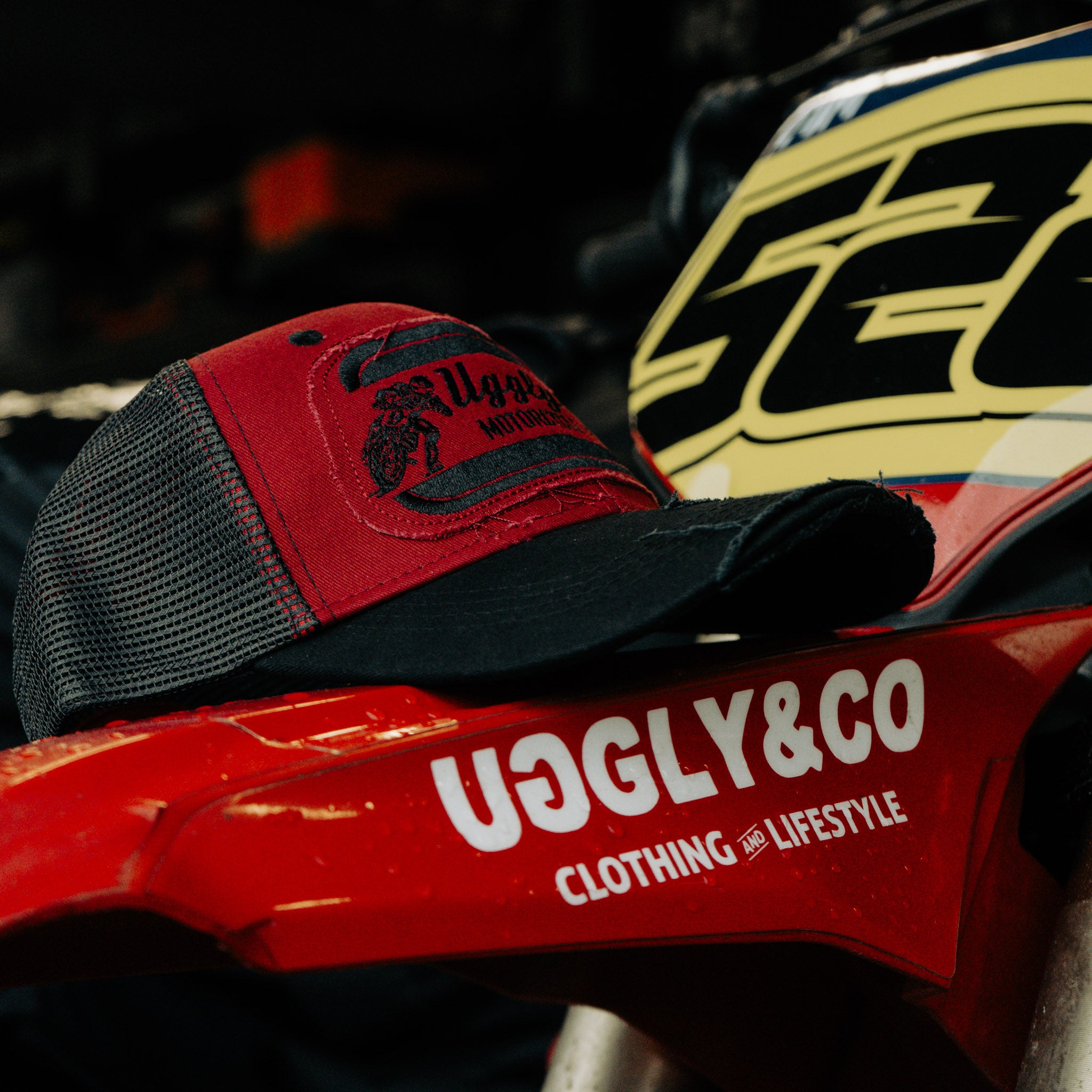 Side view of the Black & Red Flat Track Trucker Hat showing the mesh back, curved peak and motorsport-inspired patch details.