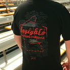 Steve Day ‘The Map’ black T-shirt shown in a race paddock and pit lane setting