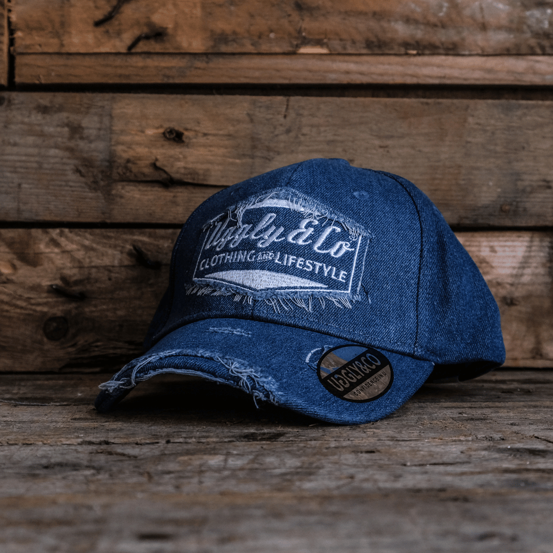 Blue denim Baseball Cap with Uggly&Co branding on a wooden background