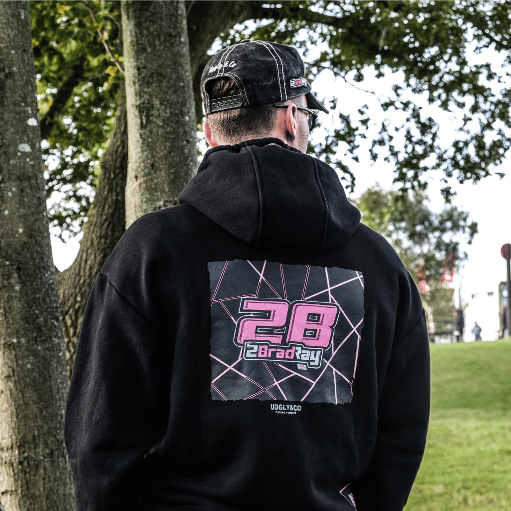 Person wearing a black hoodie with a graphic design on the back, standing outdoors.