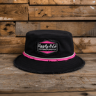 Black bucket hat with pink trim and visible brand logo on a wooden background