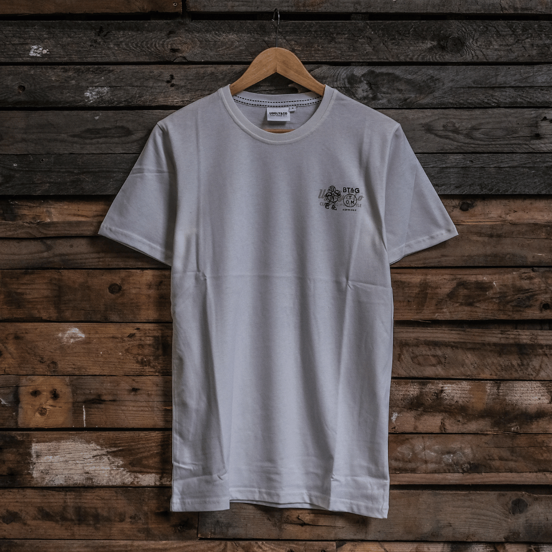 Front view of a Tom Kerridge's Butchers Tap and Grill white t-shirt with black graphics and text on a wooden background