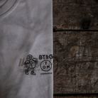 Close up of the chest logo on a Tom Kerridge's Butchers Tap and Grill white t-shirt with black graphics and text on a wooden background