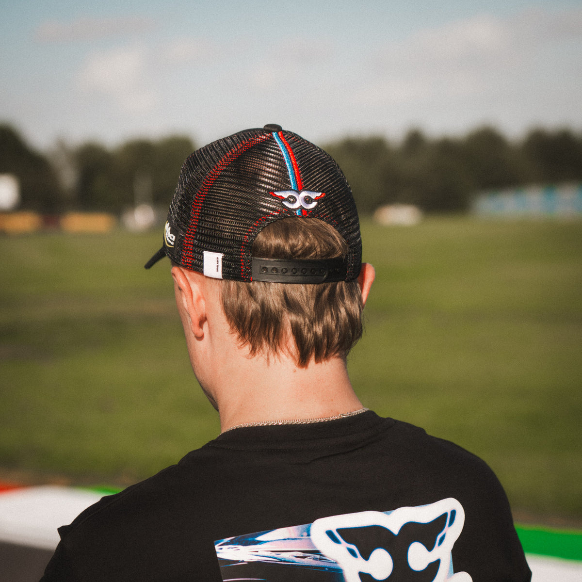 Close-up of the Carl Cox Trucker Hat collaboration design featuring Alpha Racing and Simon Reid branding, part of the Uggly & Co motorcycle lifestyle collection.